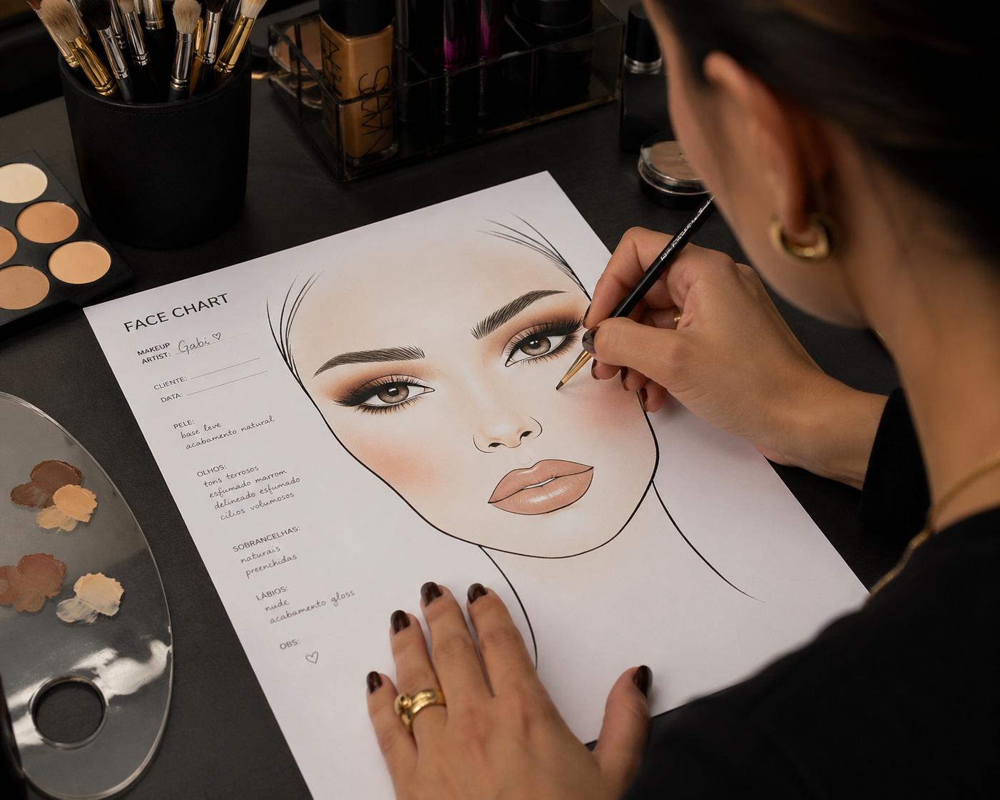 Makeup artist hand-drawing a facechart on paper, surrounded by professional brushes and palettes